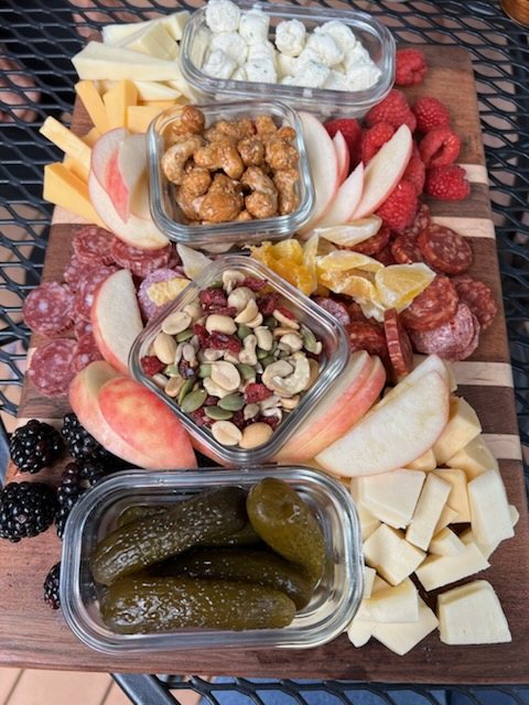 Charcuterie board with cheese, nuts, and pickles
